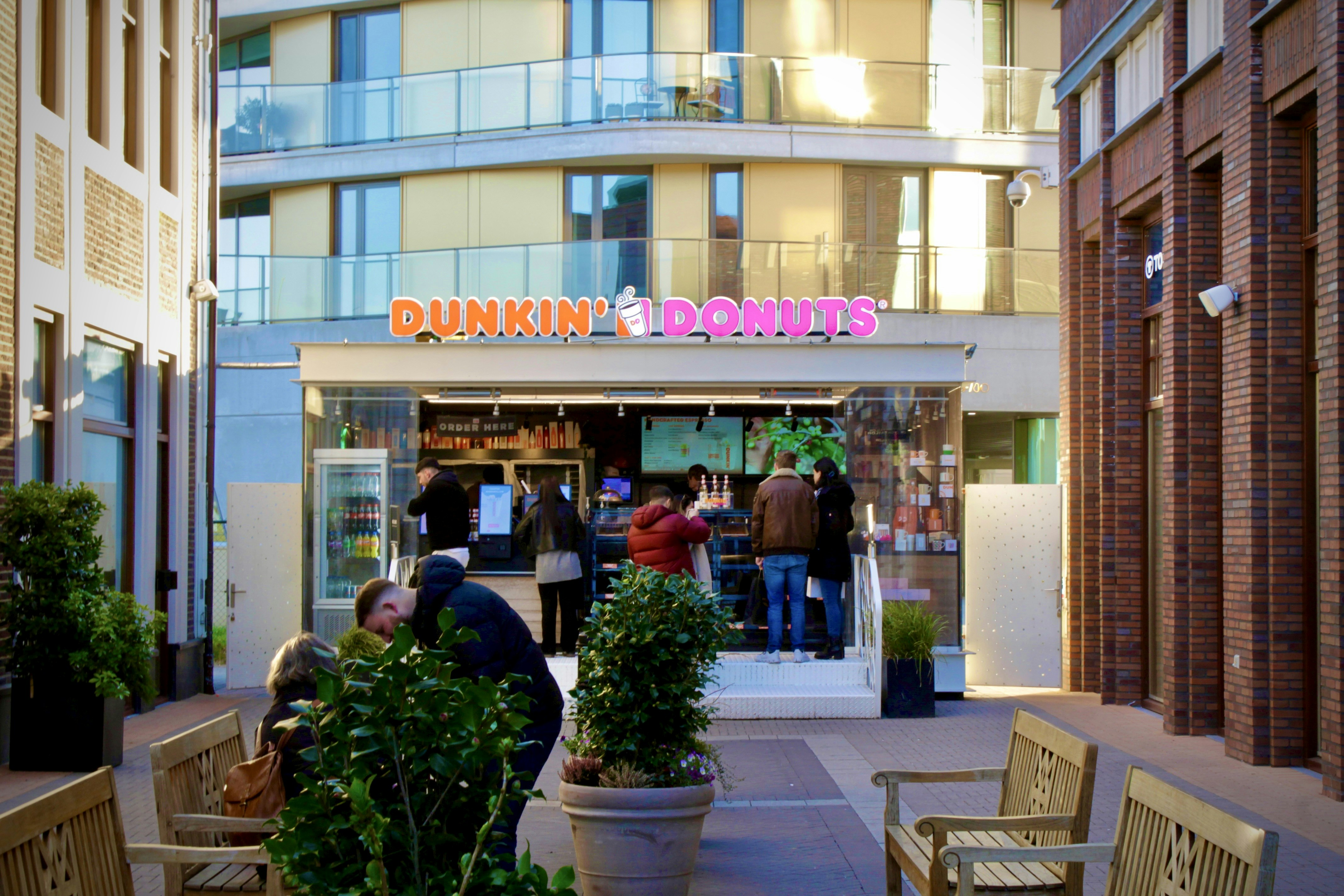 A Dunkin’ Refresher drink next to a smartphone showing an automated text message reply, illustrating the connection between a free promotion and instant lead follow-up.