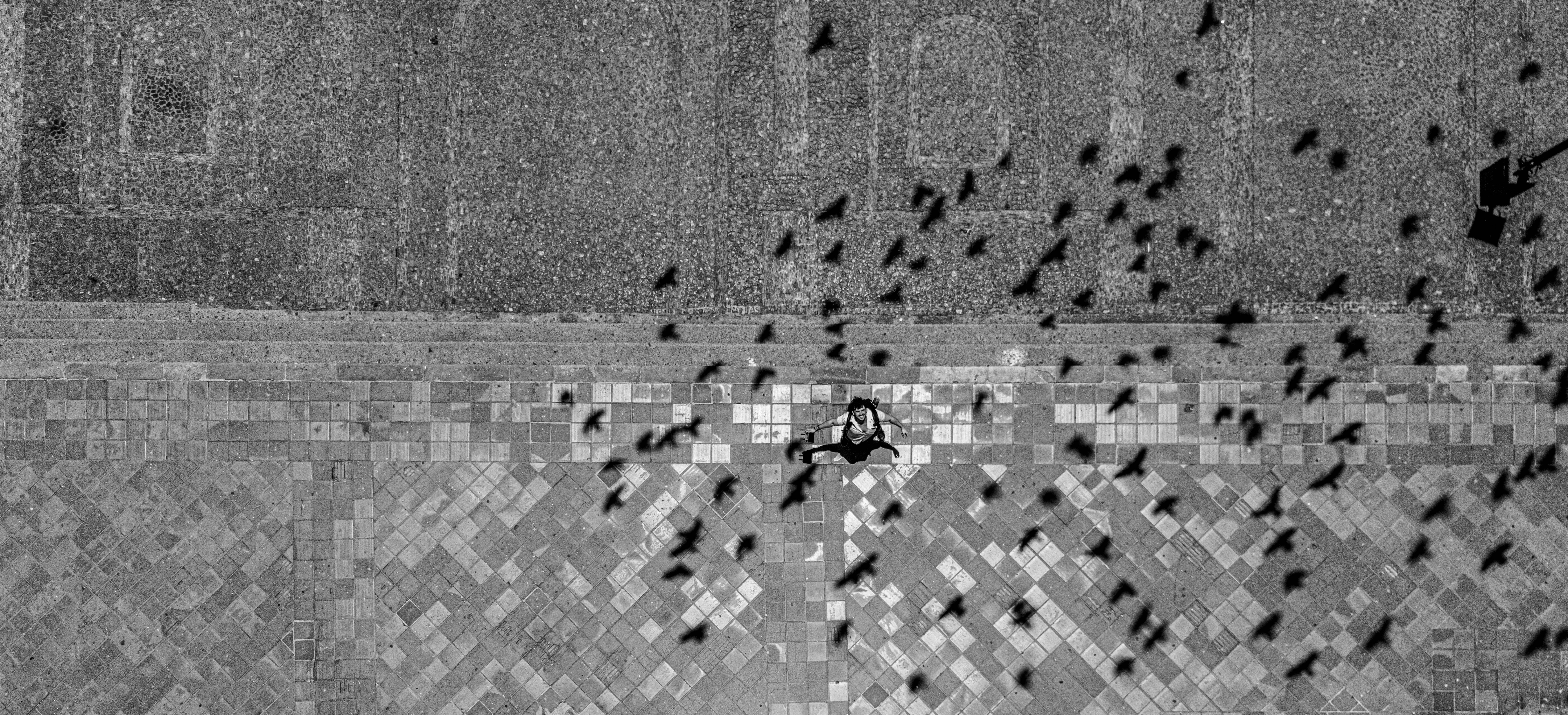 A neighborhood street with a small pole-mounted surveillance camera visible in the foreground, overlaid with a translucent digital map grid.