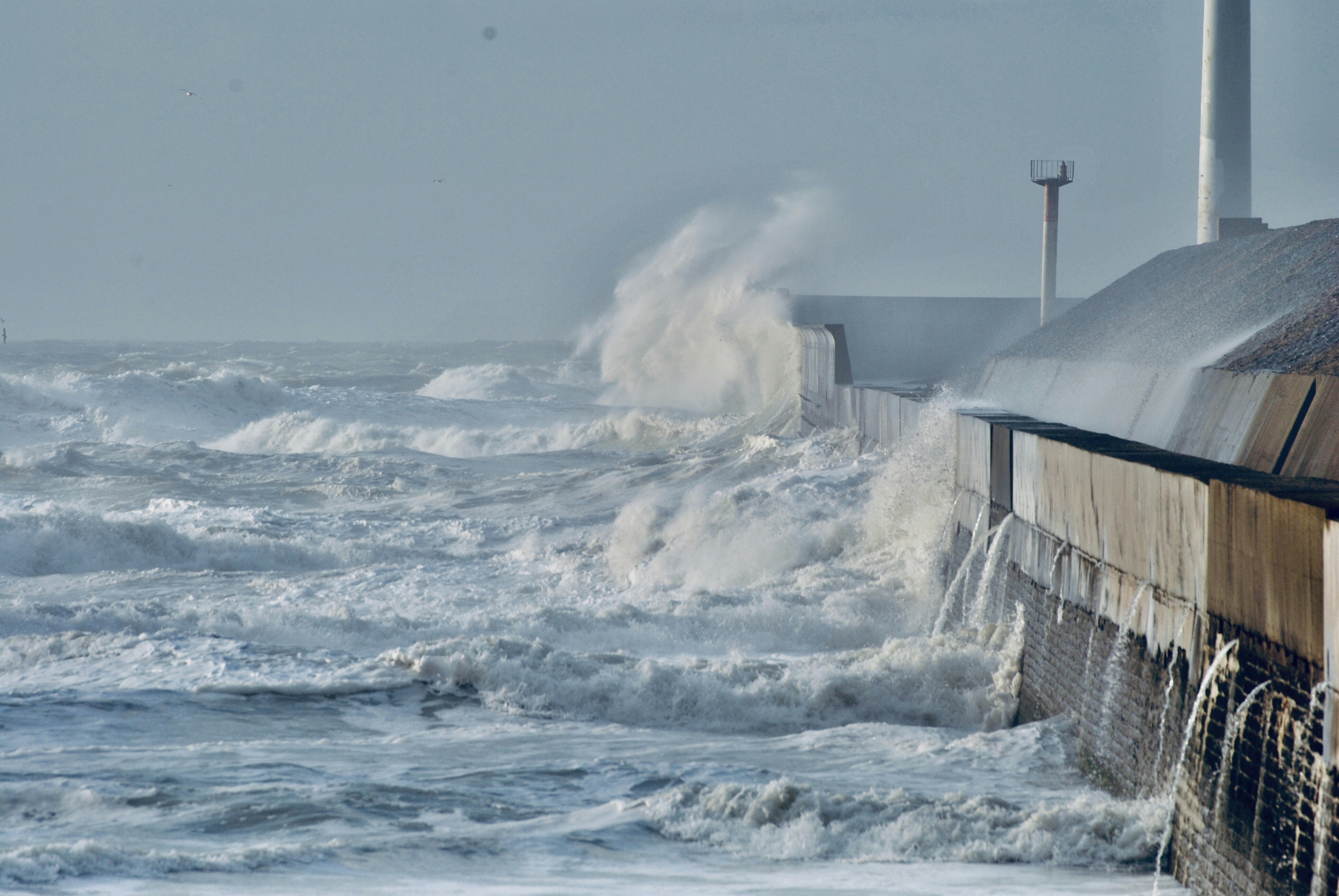 big waves crashing gray concrete building during daytime