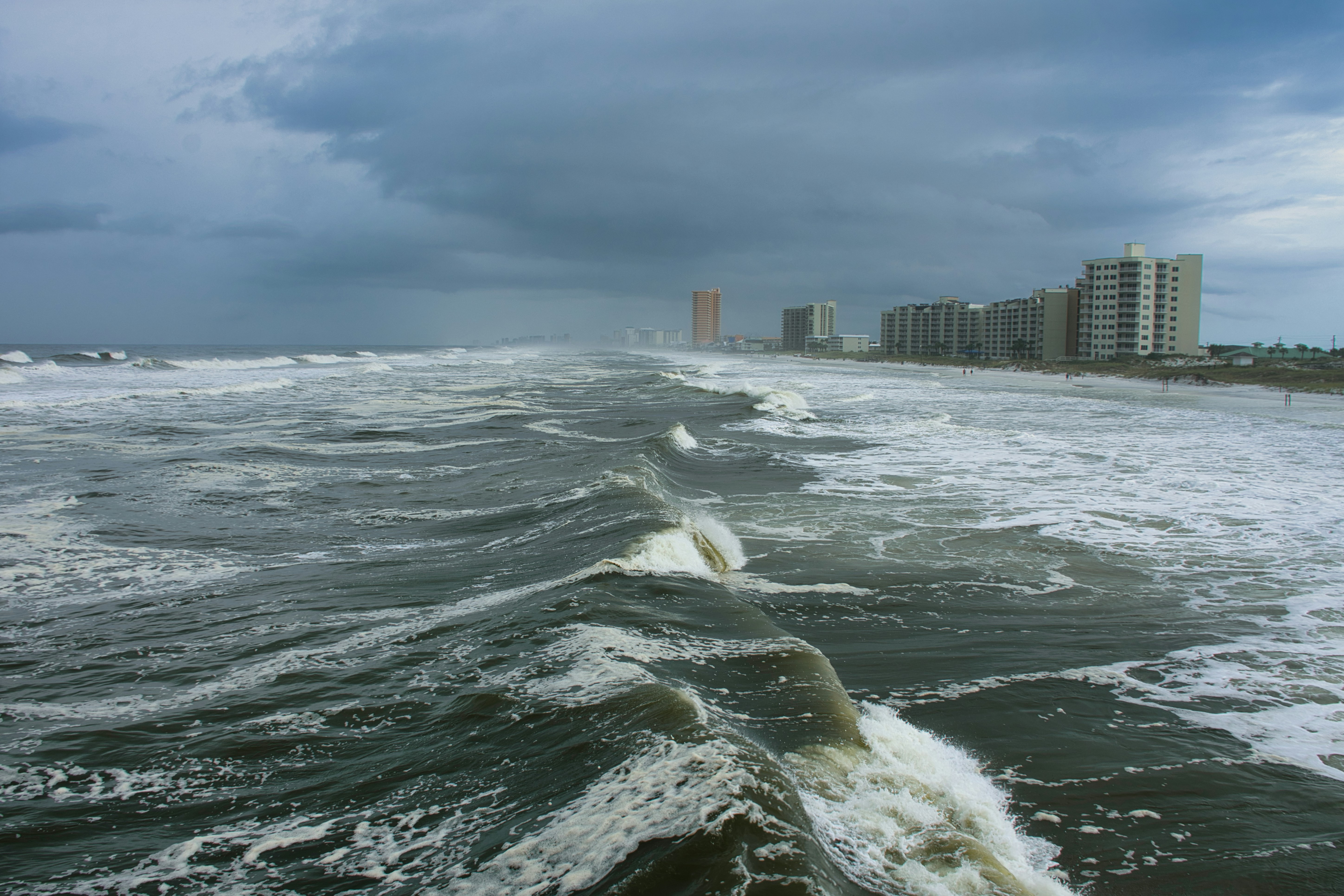 ocean waves near city buildings during daytime
